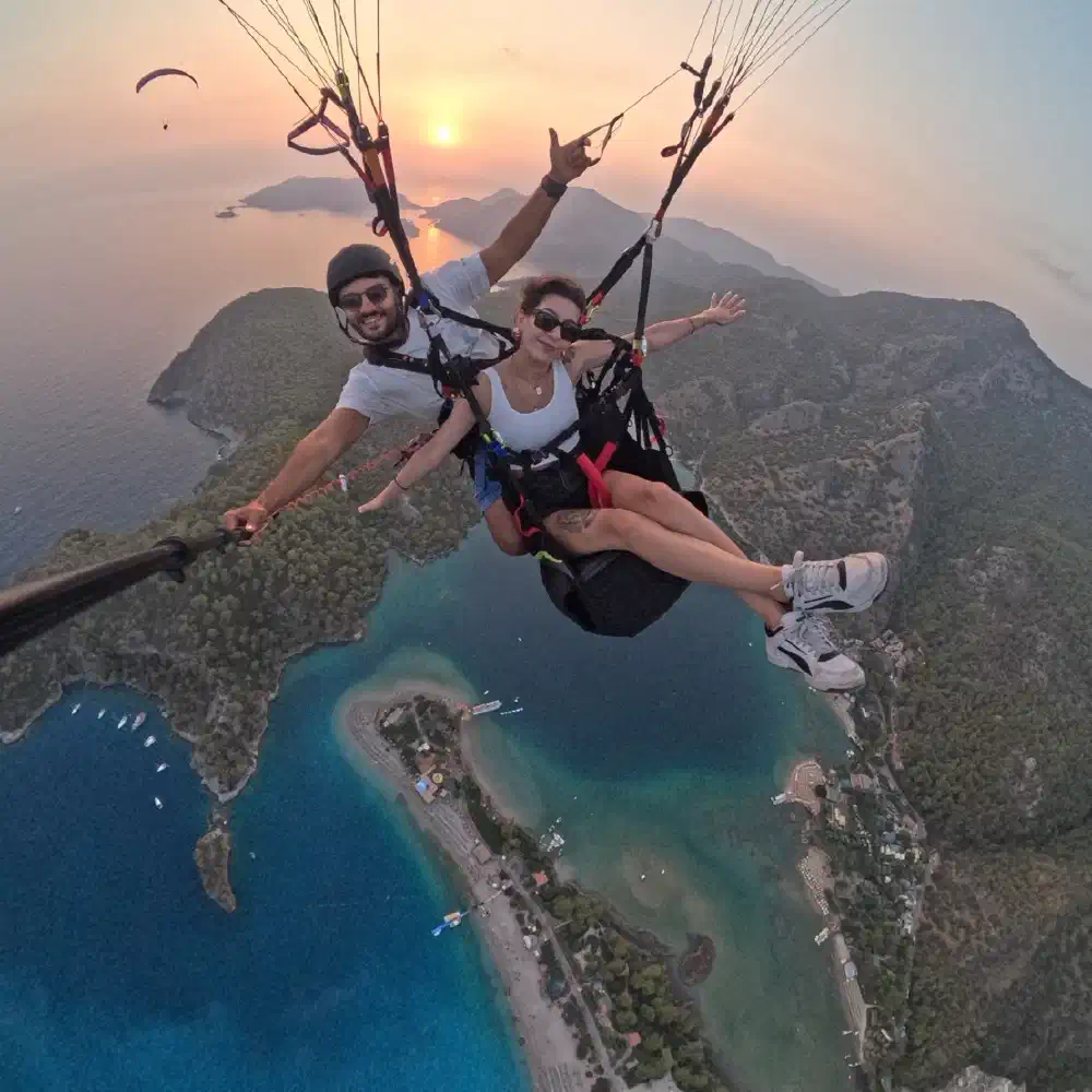 Tandem paraglider flying high above the bright blue waters of Oludeniz