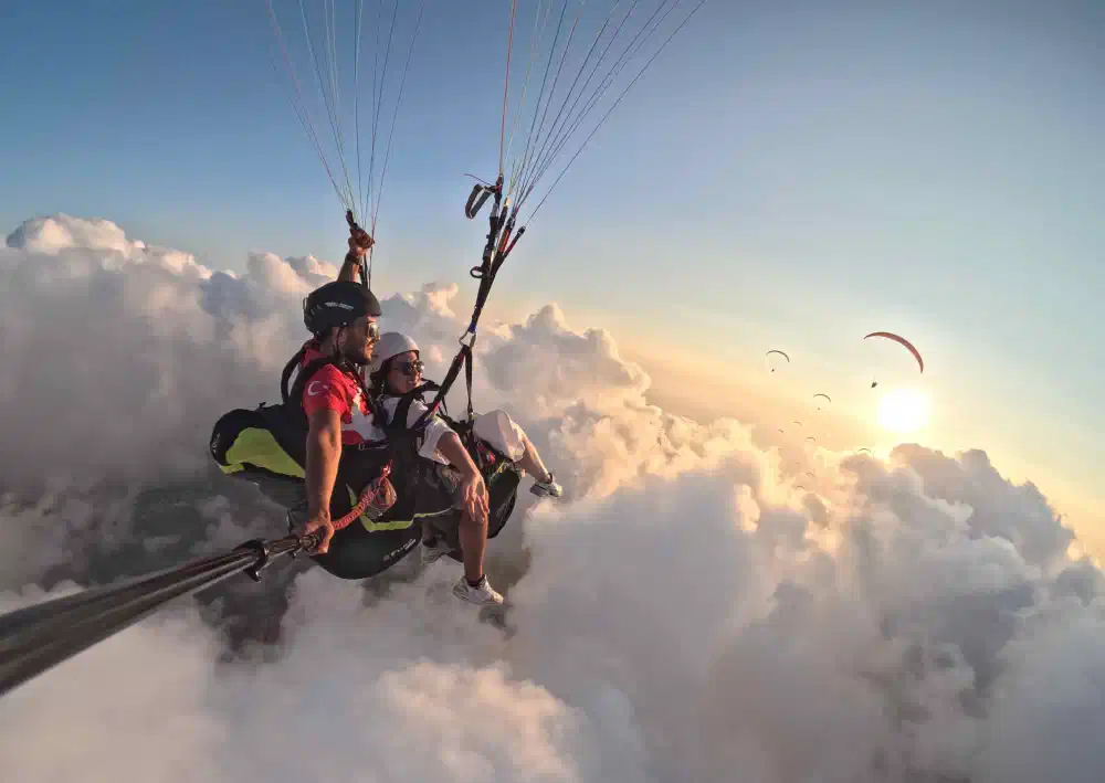 Paraglider flying playfully near a puffy white cloud in Fethiye